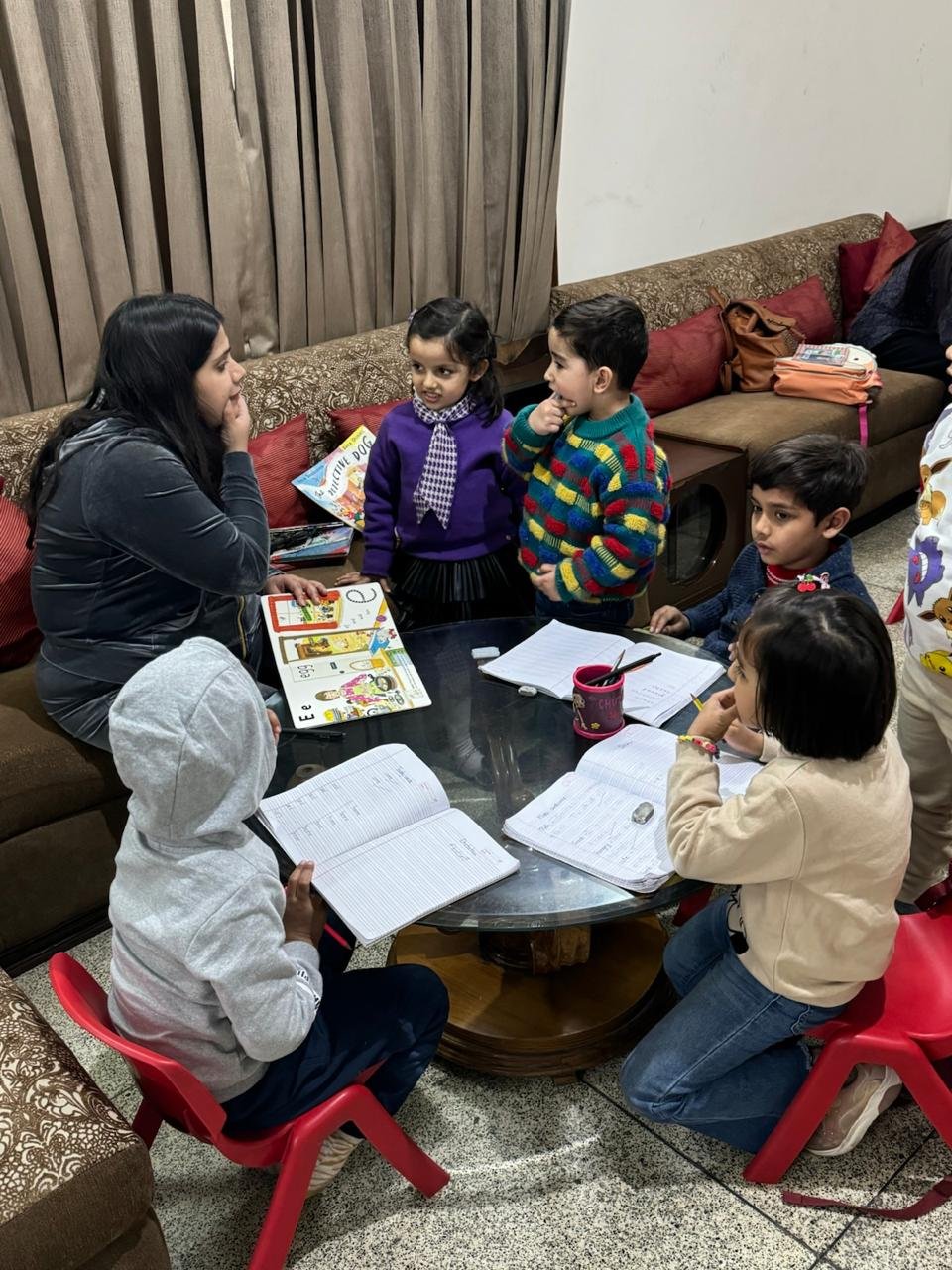Teacher supporting children with reading at The Alphabet